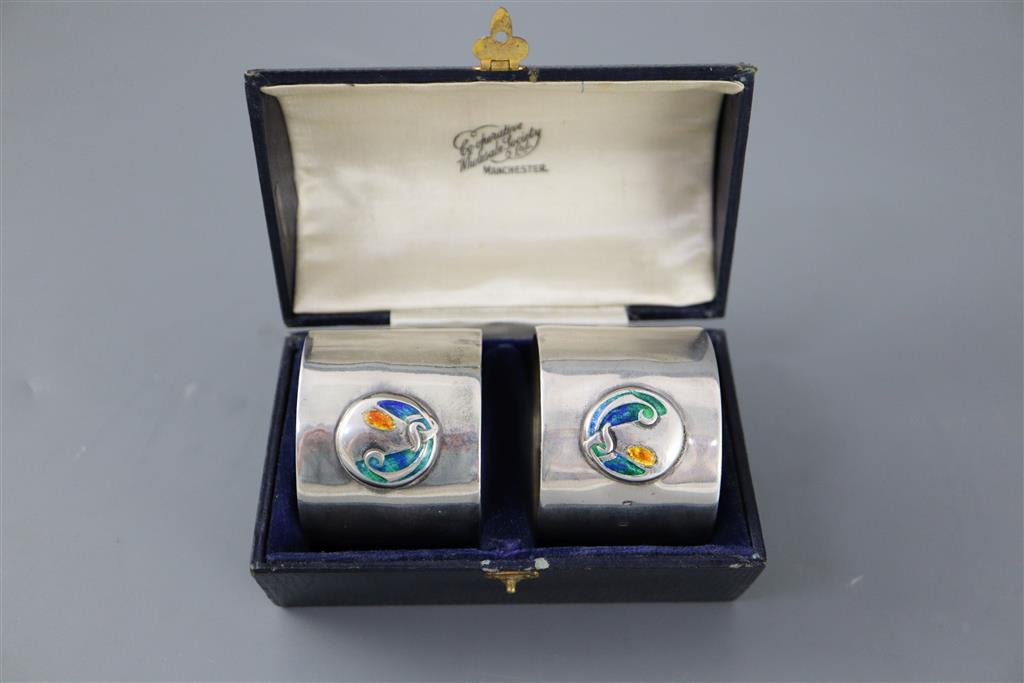 A cased pair of Edwardian Art Nouveau silver and enamel napkin rings, by William Hair Haseler,
